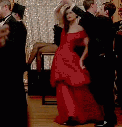 A Woman In A Red Dress Is Dancing With A Man In A Black Tuxedo . GIF