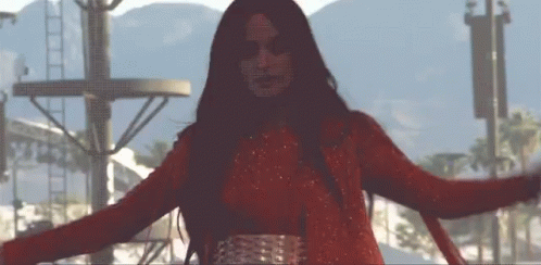 A Woman In A Red Dress Is Dancing With Her Arms Outstretched GIF