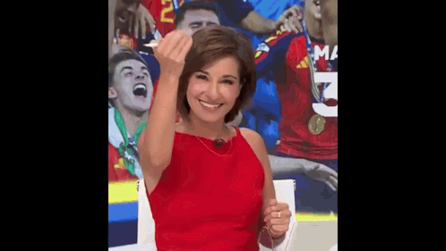 a woman in a red dress is giving a middle finger in front of a soccer team .