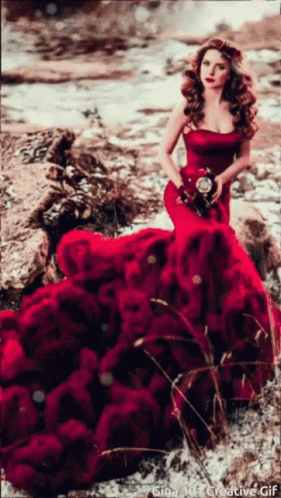 A Woman In A Red Dress Is Holding A Bouquet Of Red Roses GIF
