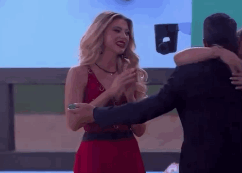 A Woman In A Red Dress Is Hugging A Man In A Black Suit GIF