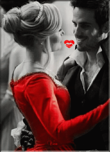 A Woman In A Red Dress Is Kissing A Man In A Black And White Photo GIF