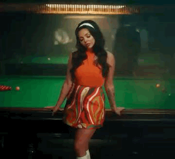 A Woman In A Red Dress Is Leaning On The Edge Of A Pool Table . GIF