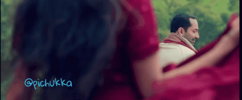 A Woman In A Red Dress Is Looking At A Man In A White Shirt With A Scarf Around His Neck GIF