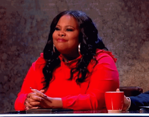 A Woman In A Red Dress Is Sitting At A Table With A Red Cup Of Coffee . GIF