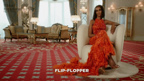 A Woman In A Red Dress Is Sitting In A Chair And The Word Flip-Flopper Is On The Carpet GIF