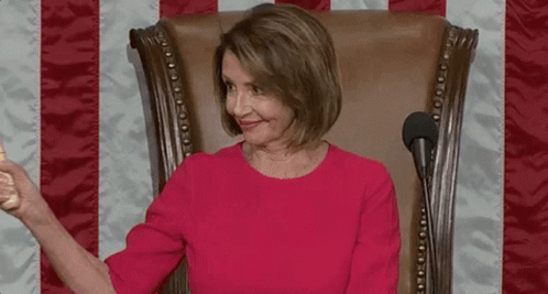 A Woman In A Red Dress Is Sitting In A Chair Holding A Wooden Hammer . GIF