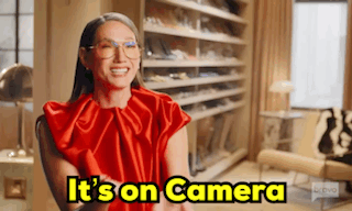 A Woman In A Red Dress Is Sitting In A Chair In Front Of A Closet . GIF