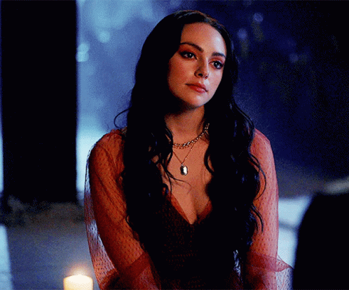 A Woman In A Red Dress Is Sitting In Front Of A Candle GIF