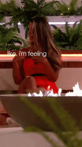 A Woman In A Red Dress Is Sitting In Front Of A Fire With The Words Like I 'M Feeling Above Her GIF
