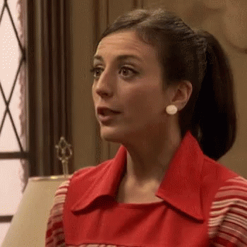 A Woman In A Red Dress Is Sitting In Front Of A Lamp In A Room . GIF
