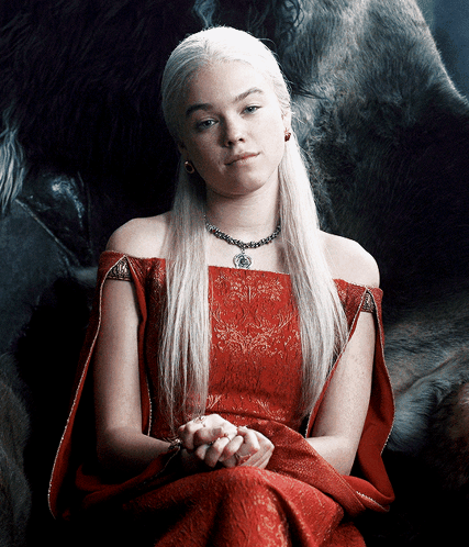 A Woman In A Red Dress Is Sitting In Front Of A Large Animal GIF