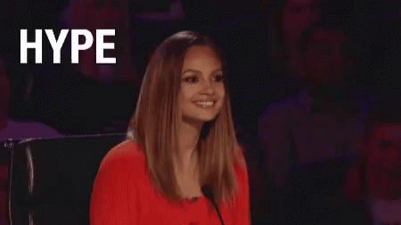 A Woman In A Red Dress Is Sitting In Front Of A Microphone And The Word Hype Is Written On The Screen . GIF