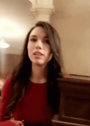A Woman In A Red Dress Is Sitting In Front Of A Piano And Making A Funny Face . GIF