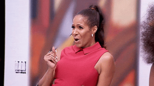 A Woman In A Red Dress Is Sitting In Front Of A Screen . GIF