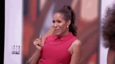 A Woman In A Red Dress Is Sitting In Front Of A Wall And Crying . GIF