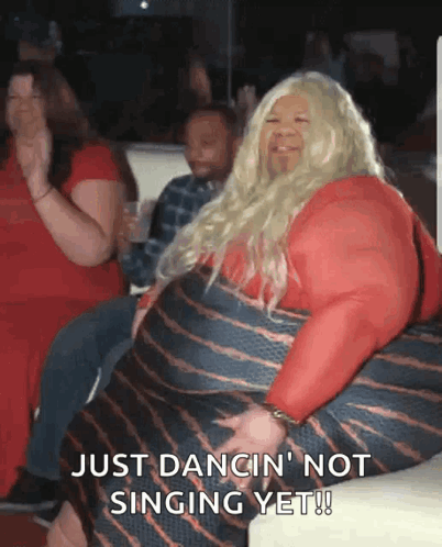 A Woman In A Red Dress Is Sitting On A Couch And Says Just Dancin ' Not Singing Yet ! GIF