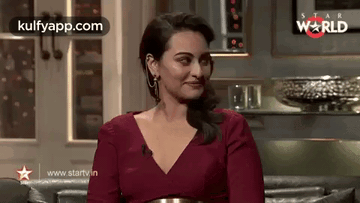 A Woman In A Red Dress Is Sitting On A Couch In A Living Room . GIF