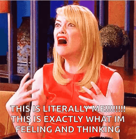 A Woman In A Red Dress Is Sitting On A Couch With Her Mouth Open And Making A Funny Face . GIF