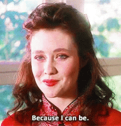 A Woman In A Red Dress Is Smiling And Saying Because I Can Be . GIF