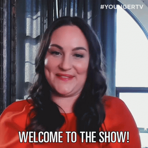 A Woman In A Red Dress Is Smiling And Says Welcome To The Show GIF