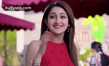 A Woman In A Red Dress Is Smiling While Standing In Front Of A Restaurant . GIF
