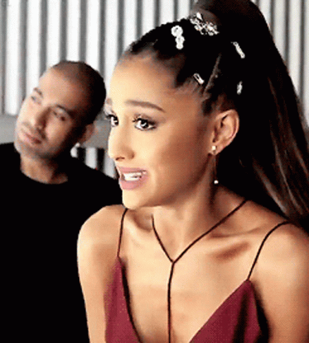 A Woman In A Red Dress Is Smiling With A Man In The Background . GIF