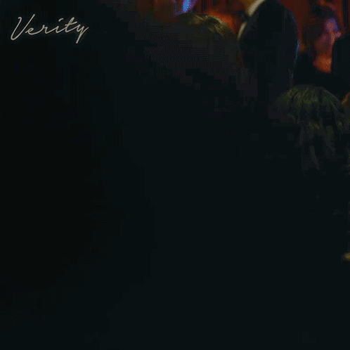 A Woman In A Red Dress Is Standing At A Bar With The Word Verity Written On The Bottom GIF