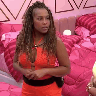 A Woman In A Red Dress Is Standing In A Bedroom With Pink Pillows . GIF