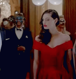 A Woman In A Red Dress Is Standing In A Hallway With People In Masks GIF