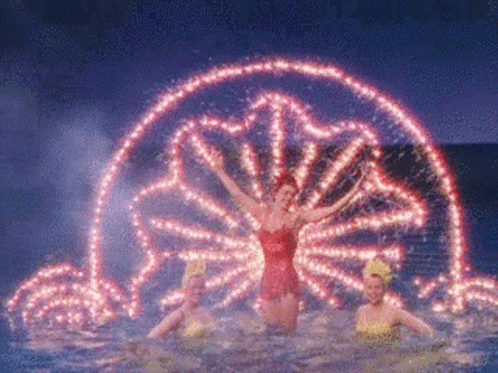 A Woman In A Red Dress Is Standing In A Pool Of Water GIF