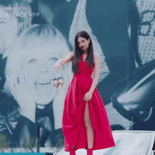 A Woman In A Red Dress Is Standing In Front Of A Car With A Reface App Logo On The Bottom GIF