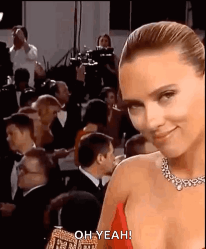 A Woman In A Red Dress Is Standing In Front Of A Crowd Of People At An Event . GIF