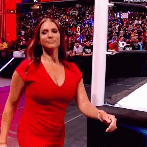 A Woman In A Red Dress Is Standing In Front Of A Crowd With A Sign That Says The Next Thing GIF