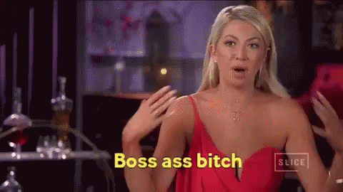 A Woman In A Red Dress Is Standing In Front Of A Table And Says Boss Ass Bitch . GIF