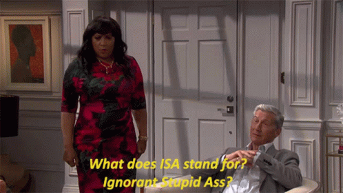 A Woman In A Red Dress Is Standing Next To A Man In A Suit Who Is Sitting In A Chair GIF
