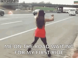 A Woman In A Red Dress Is Standing On The Side Of A Highway . GIF