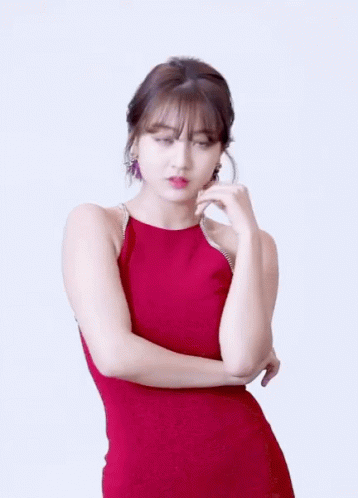 A Woman In A Red Dress Is Standing With Her Hands Crossed GIF