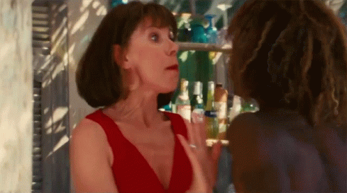 A Woman In A Red Dress Is Talking To Another Woman In A Bar GIF
