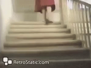 A Woman In A Red Dress Is Walking Down A Set Of Stairs With Retrostatic.com In The Corner GIF