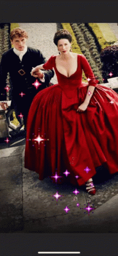 A Woman In A Red Dress Is Walking Next To A Man In A Black Suit GIF