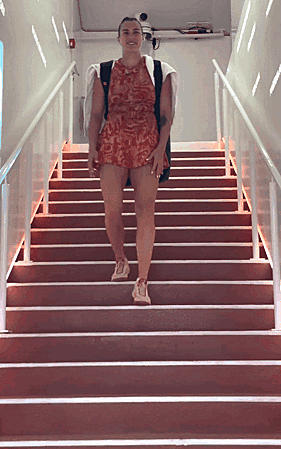 A Woman In A Red Dress Is Walking Up A Set Of Red Stairs GIF