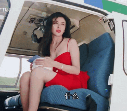 A Woman In A Red Dress Sits In A Helicopter GIF