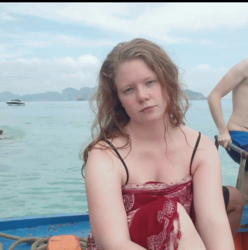 A Woman In A Red Dress Sits On A Boat GIF