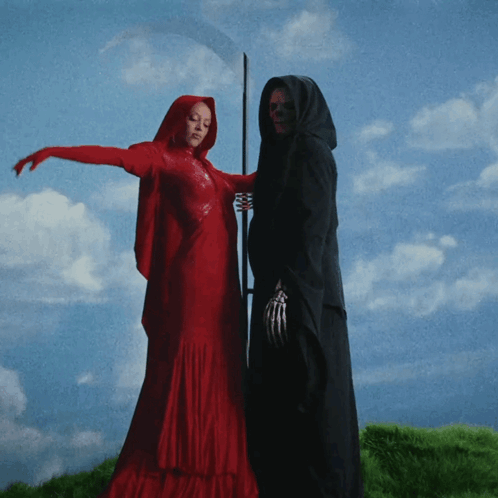 A Woman In A Red Dress Standing Next To A Grim Reaper GIF
