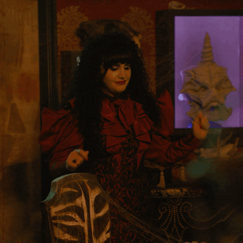 A Woman In A Red Dress Stands In Front Of A Display Case With A Skull In It GIF