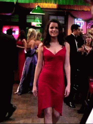 A Woman In A Red Dress Walks Through A Crowd GIF