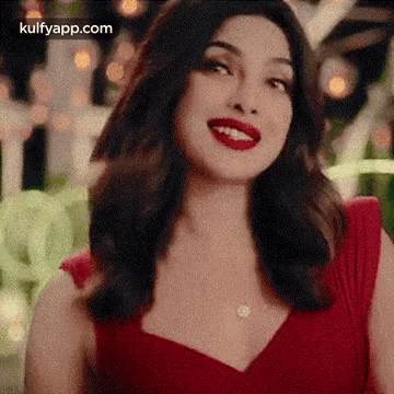 A Woman In A Red Dress With Red Lipstick Is Smiling . GIF