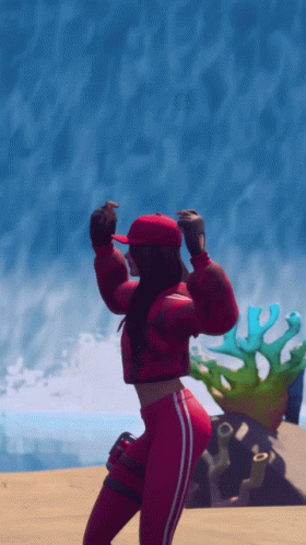 A Woman In A Red Jacket And Red Hat Is Dancing On The Beach GIF