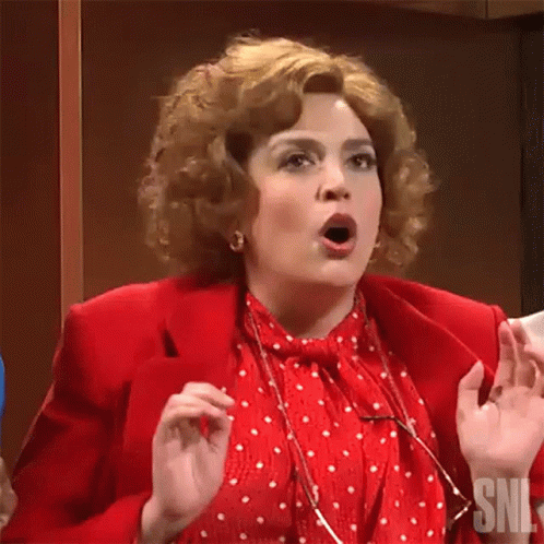 A Woman In A Red Jacket And White Polka Dot Shirt Is Making A Surprised Face . GIF
